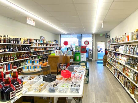 Gaslite Liquors Interior – Wide Selection & Convenient Amenities Bright, organized interior of Gaslite Liquors in North Charleston, featuring well-stocked shelves of spirits and wine. The foreground shows a variety of miniature liquor bottles and barrel displays, while the background highlights the SC Education Lottery